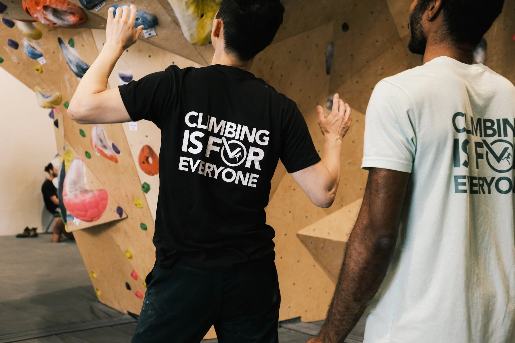 A climber wearing a Climbing is for Everyone shirt inside the gym.